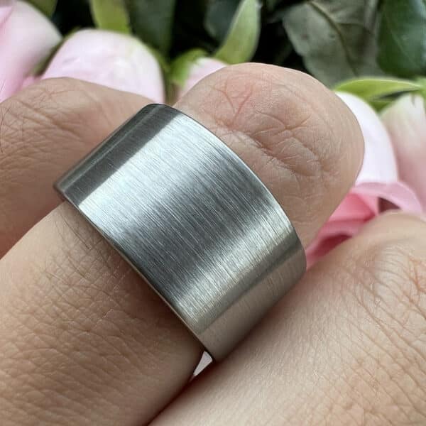 A finger wearing the unique 12mm tungsten men's band and showcasing its brushed finish and pipe cut edges.