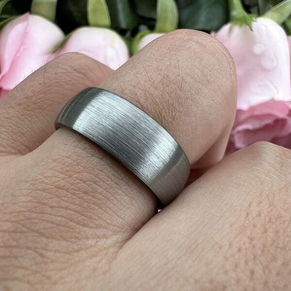 A gray contemporary and simple men's wedding ring with a brushed finish on a ring finger.
