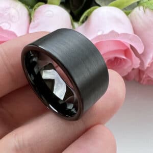 A 12mm unique black tungsten men's wedding band that features a brushed finish, pipe cut edges, and polished sleeve.
