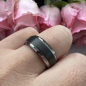 A ring finger wears The Shawn to show its simple aura through its black brushed center, silver edges, and black smooth sleeve.