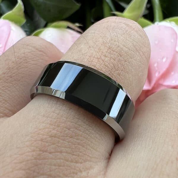 A ring finger showcasing the uniqueness of The Price through its black tungsten material, polished finish, and silver edges.