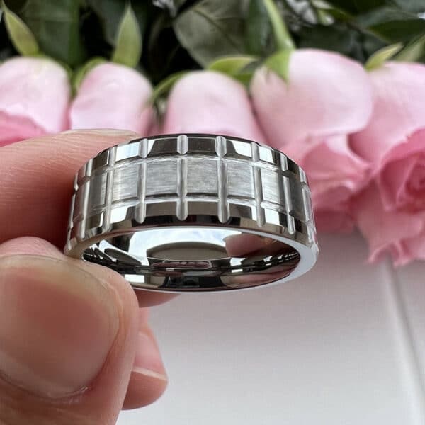 Three fingers bear a 8mm matrix design men's wedding band with a brushed center and polished edges and sleeve.