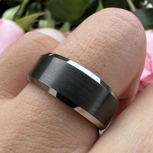 A ring finger wearing The Paul, showcasing its black magnificence through its brushed center and polished edges.