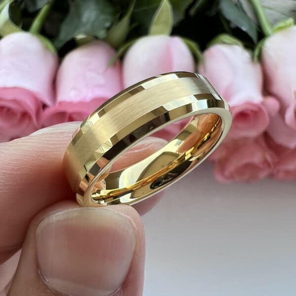 An 18K gold-plated 6mm men's wedding band featuring a brushed center and polished beveled edges held with three fingers.