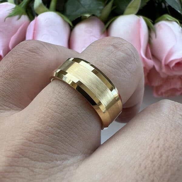 A ring finger wears The Blake and showcases its 18K gold-plate, brushed center, and polished beveled edges.