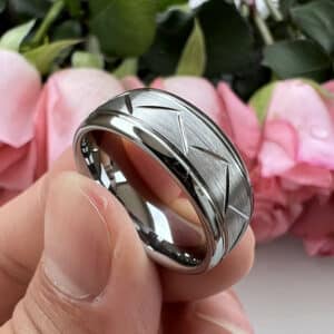 A cut-through pattern design men's ring with a brushed finish and polished edges and sleeve, resting amidst three fingers.