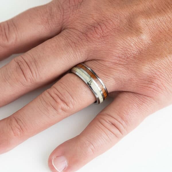 A hand showing off a polished tungsten carbide wood embedded ring and its snug fitting.