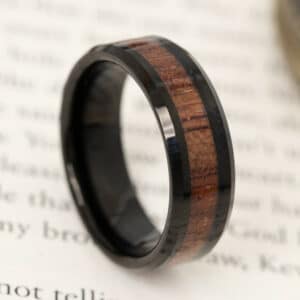 A men’s tungsten wedding band made with embedded koa wood and black sleeves.