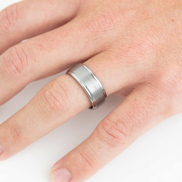 A spread out hand with the ring finger displays a 9mm contemporary wedding ring featuring a brushed center, polished edges, and sleeve.