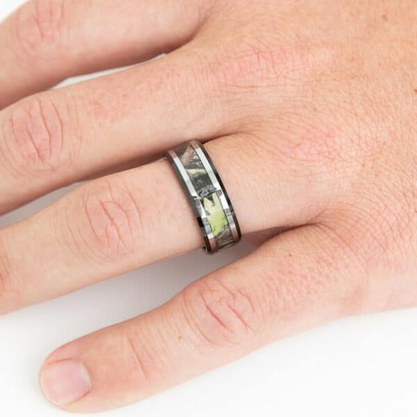 A black tungsten men's wedding ring, showing its camo inlay, silver and black edges, and polished finish.