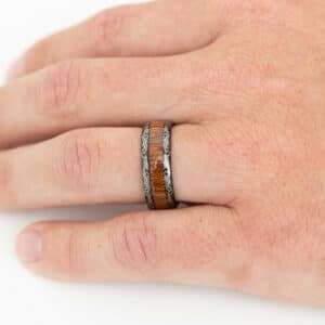 A ring finger wears the The Bennett to show its unique laser etched design, KOA wood center, and polished finish.