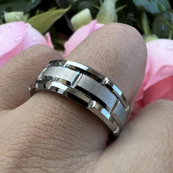 A 8mm wedding band for men with a carved pattern design, polished edges, and brushed center on a ring finger.